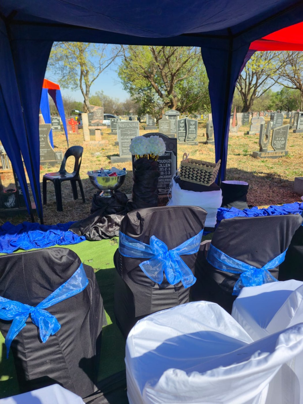 A funeral gathering arranged beneath a canopy